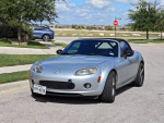2006 Mazda MX5 Miata silver sports car parked on the street, showcasing its sleek design and low mileage.