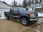 2005 GMC 2500 SLT Duramax truck with gray leather interior, parked in front of a garage.
