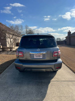 Rear view of a 2019 Nissan Armada SL in silver, parked on a driveway, showcasing its sleek design.