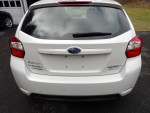 Rear view of a 2015 Subaru Impreza in pearl white, showcasing its clean shape and premium features.