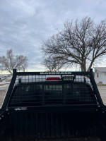 Rear view of a 2005 Toyota Tacoma with Backrack and light bar against a cloudy sky.