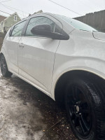 2016 Chevrolet Sonic LT hatchback in white with black rims parked on a wet surface