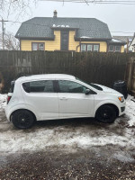 2016 Chevrolet Sonic LT hatchback in white with black rims parked in snowy backyard
