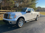 White Ford F150 truck parked on a country road, showcasing its excellent condition and features.