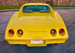 Rear view of a fully restored 1974 Chevrolet Corvette in bright yellow with distinctive tail lights.