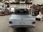 1972 BMW 2002 Tii rear view in a garage with tan Recaro seats and black interior.