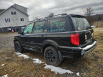 2003 Honda Pilot SUV in black with third-row seating and new tires, parked in a rural area.