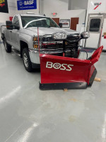 2015 Chevrolet Silverado 2500HD 4X4 with BOSS plow in a clean showroom, ideal for snow removal and heavy-duty use.