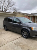 2017 Dodge Grand Caravan parked in driveway, featuring dual sliding doors and a clean exterior.