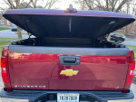 Rear view of a red 2013 Chevrolet Silverado 1500 with an open bed cover, showcasing its sleek design and features.