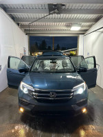 Front view of a 2017 Honda Pilot EX-L with open doors, showcasing its sleek design and clean interior.