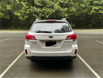 Rear view of a 2011 Subaru Outback 2.5i AWD parked in a forested area, showcasing its clean design.
