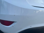 Close-up of the rear bumper of a white 2015 Ford Fiesta showing minor scratches and scuffs.