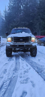 Front view of a lifted 2001 Ford F350 in snowy surroundings, highlighting its off-road features.