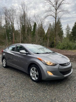 2013 Hyundai Elantra GLS in gray parked outdoors with trees in the background, featuring low mileage and well-maintained condition.