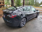 2018 Tesla Model 3 Mid Range RWD parked in a natural setting, showcasing its sleek design and new tires.