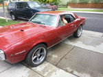 1967 Pontiac Firebird in red with aftermarket wheels, parked on the street.