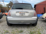 Rear view of a 2004 MINI Cooper parked, showing its silver exterior and unique design.