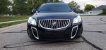 Front view of a rare 2013 Buick Regal GS in metallic black with headlights on, parked on the street.