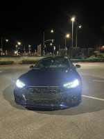2021 Audi RS5 Sportback in dark blue with LED headlights, parked at night in a well-lit area.