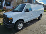 2012 Ford E-250 work van with storage cabinets, parked in a residential area, well-maintained and accident-free.