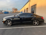 2012 Mercedes-Benz CLS550 in black with cream leather interior parked outside, featuring sleek design and alloy wheels.