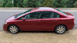 2010 Honda Civic LX in red, 99,947 miles, parked with minor wear and tear details visible.