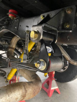 Close-up of modified suspension components on a 1990 Dodge Ramcharger 4x4, showcasing coilovers and shackle bracket.