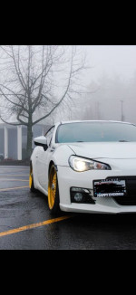 2015 Subaru BRZ in near mint condition with gold wheels and mods, parked on a rainy day.