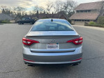 Rear view of a 2015 Hyundai Sonata parked on a road, showcasing its sleek design and good condition.