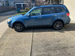 2009 Subaru Forester 2.5X AWD wagon parked on driveway, featuring a blue exterior and clean condition.