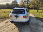 2008 GMC Acadia in pearl white with black leather interior, parked on a gravel road in scenic surroundings.