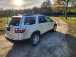 2008 GMC Acadia in pearl white with black leather interior parked on a dirt road, showcasing a sun roof and modern features.