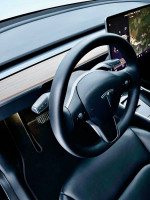Interior view of a 2021 Tesla Model Y showing the steering wheel and dashboard features.