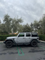 2019 Jeep Wrangler Sport 4WD parked in a lot, featuring a removable hardtop and premium wheels.