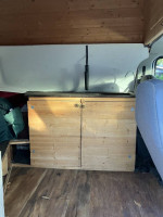 Interior view of a 2003 camper van featuring wooden cabinets and ample storage space.