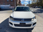Front view of a 2012 Volkswagen Touareg, white SUV, located in a city setting.