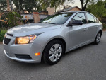 2014 Chevrolet Cruze LS in silver with black and gray cloth interior, parked on a road, showcasing its clean condition.