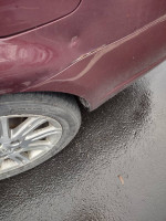 Close-up of a maroon Toyota Avalon showing minor blemishes on rear panel and alloy wheel detail.