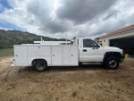 2001 Chevrolet Silverado 3500 service body truck with storage drawers and ladder rack in rural setting.