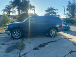 Side view of a 2002 Chevrolet Tahoe with 22-inch rims parked in a driveway.