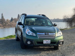 2013 Subaru Outback parked by a river, showcasing its exterior condition and new tires.
