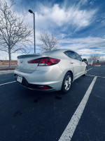 2019 Hyundai Elantra SEL sedan in silver parked with trees and cloudy sky in the background.