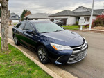 2015 Toyota Camry XLE in blue parked in a neighborhood with a clean exterior and modern design.