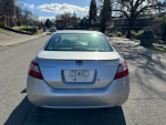 Back view of a silver 2011 Honda Civic Coupe parked on a residential street with clear skies.