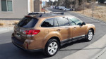 2012 Subaru Outback 2.5i AWD parked on a residential street, showcasing its bronze exterior and new tires.