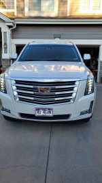 Front view of a 2017 Cadillac Escalade Platinum in Diamond White color, parked in a driveway.