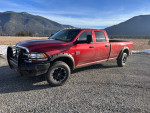 2012 Ram 2500 Power Wagon 4WD in red with rugged tires parked in a scenic landscape.
