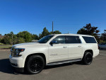 2015 Chevrolet Suburban LTZ with stylish black wheels parked under a clear blue sky
