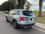 2020 Honda Pilot Touring in silver parked by the street, featuring sleek design and palm trees in the background.